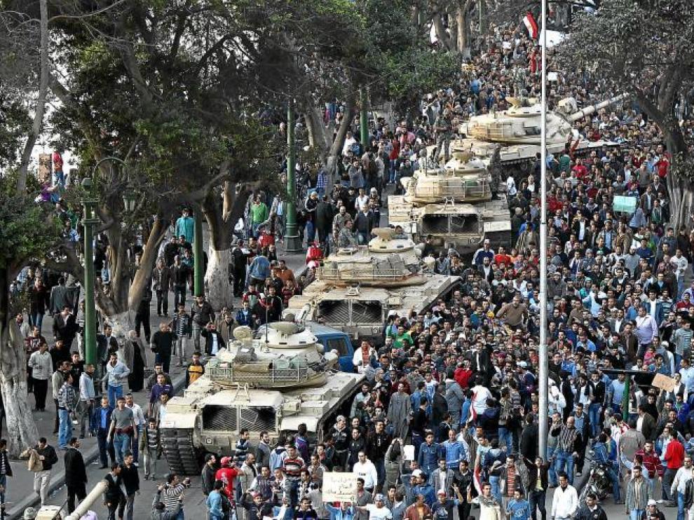 Varios tanques circulan por una calle de El Cairo rodeados por miles de egipcios.