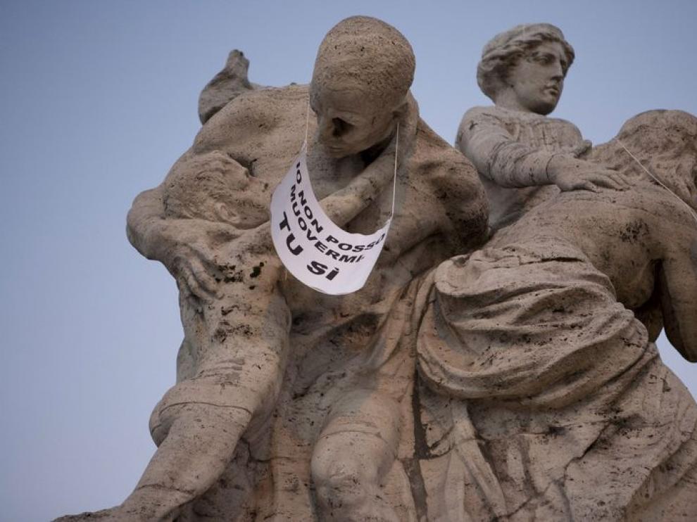 Fotografía cedida por Nessun Dorma que muestra una estatua con un cartel en el que se lee «Yo no puedo moverme. Tu si»