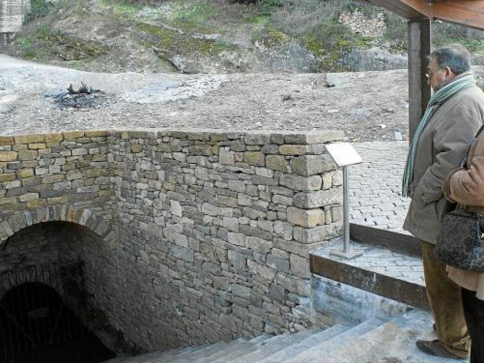 Unos visitantes observan la entrada al pozo moro, sobre la que se ha construido una pérgola.