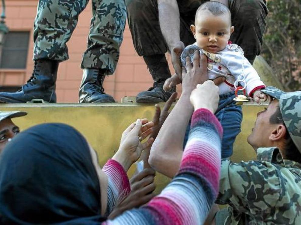 Una mujer egipcia coge a su hijo de manos de un soldado, ayer en la plaza de Tahrir.