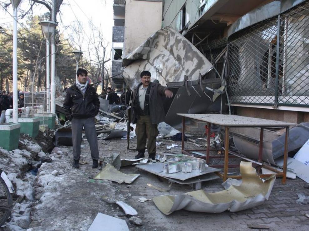 Unos hombres observan los escombros dejados por la explosion en el hotel de Kabul
