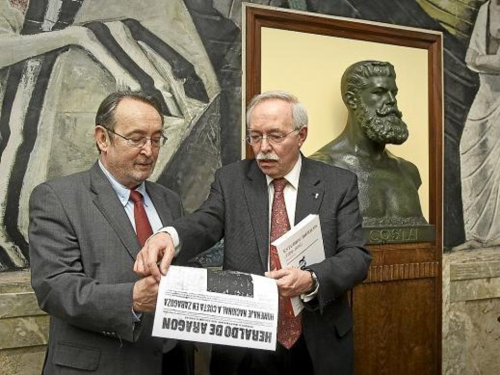 Carlos Forcadell (izquierda) y Guillermo Fatás leen sobre Costa en una edición antigua de HERALDO.
