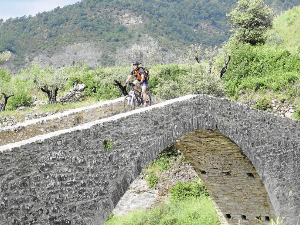 Un ciclista de BTT transita por un puente rehabilitado de la comarca de la Ribagorza donde Aramón Bike, también está presente.