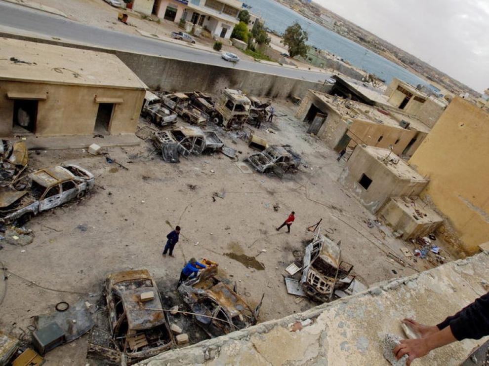 Un niño observa los vehículos quemados en el patio de una estación de policía en Tobruk (Libia)