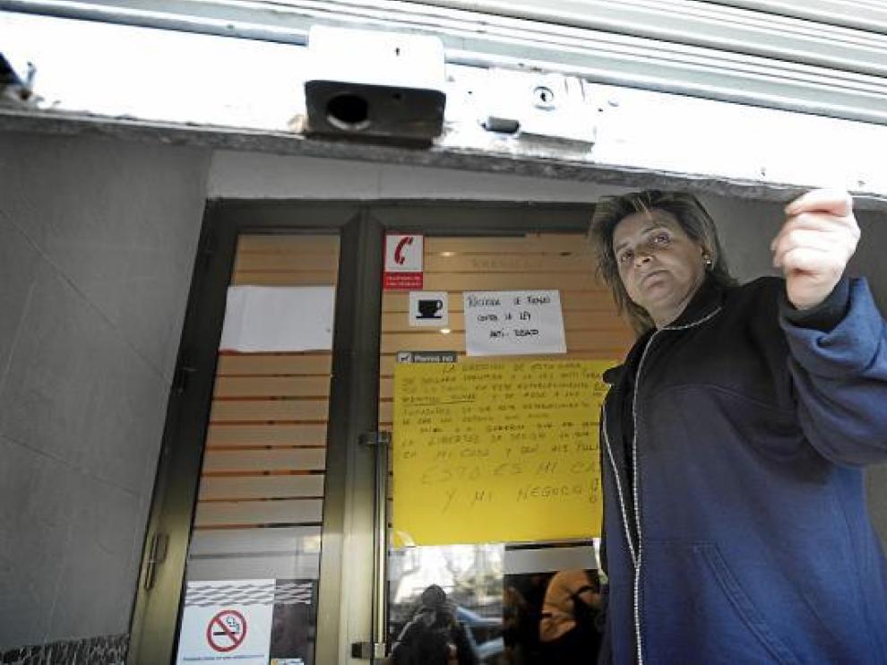 Miren Jerez cierra la persiana de su bar, donde se ve el cartel de insumisión a la ley.