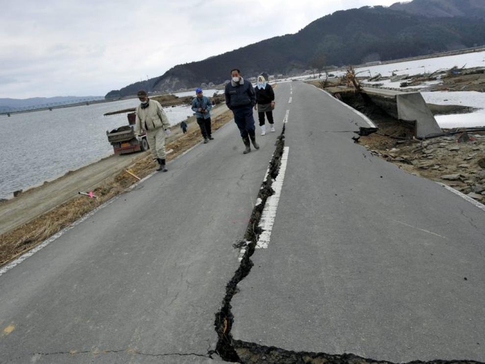 Un grupo de personas caminan por una carretera afectada por el terremoto y posterior tsunami