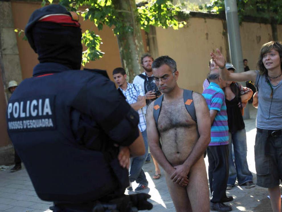 Una persona desnuda protesta ante un policía autonómico en la calle Wellington esquina con la de Villena