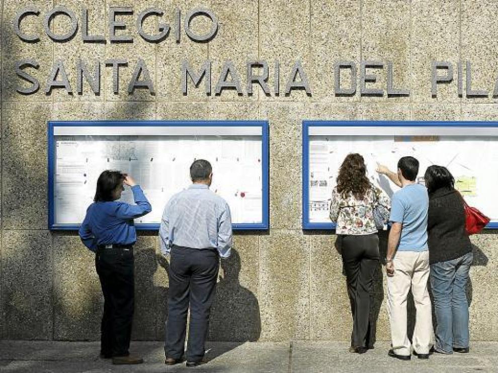 Unos padres leen los anuncios del tablón situado en la entrada de Marianistas.