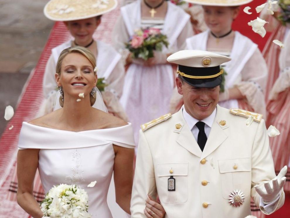 El príncipe Alberto II de Mónaco (d) y la princesa Charlene saludan a los invitados mientras abandonan el Palacio Real