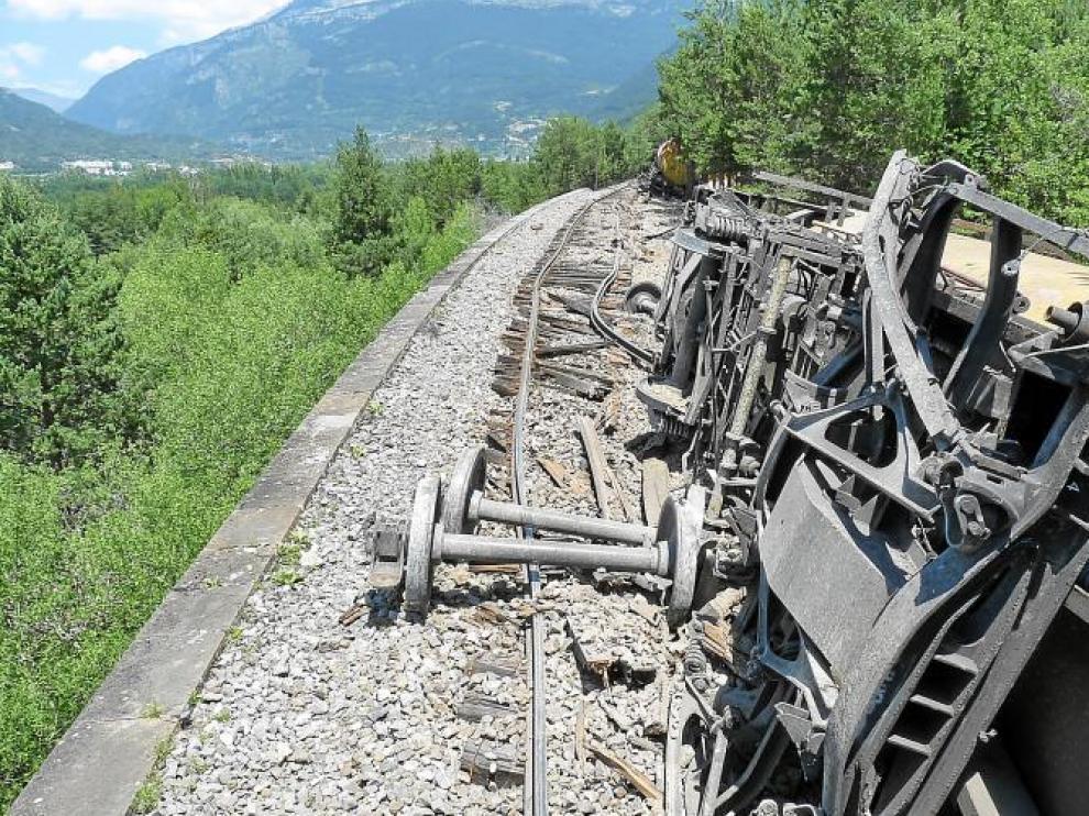 Uno de los cuatro vagones tolva volcados, con uno de los bogies muy dañado sobre la vía destrozada. Al fondo, Collarada.