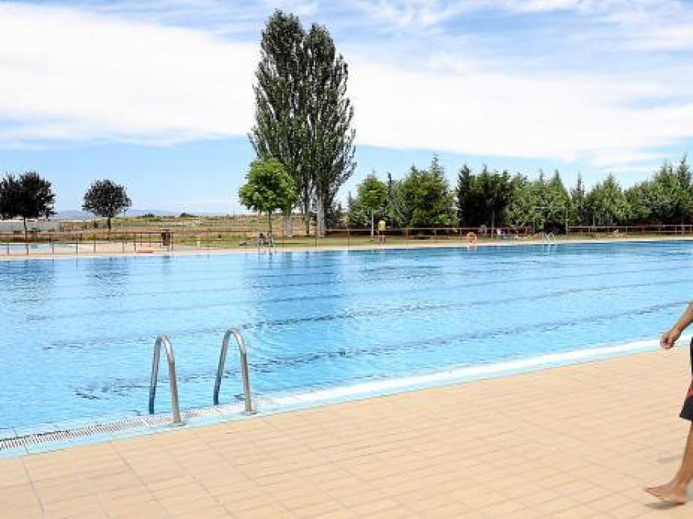 El socorrista, con una sudadera puesta, pasea por el borde de la piscina vacía de Los Planos.