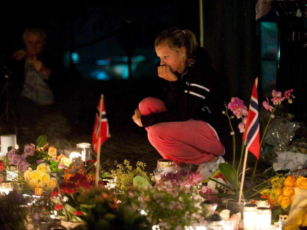 Una mujer permanece frente a las ofrendas dejadas en una iglesia de Oslo