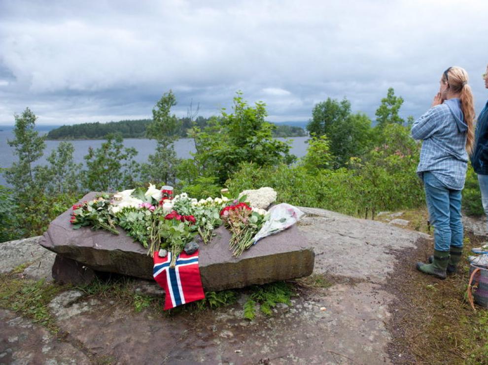 Algunas personas colocan flores frente a la isla de Utoya