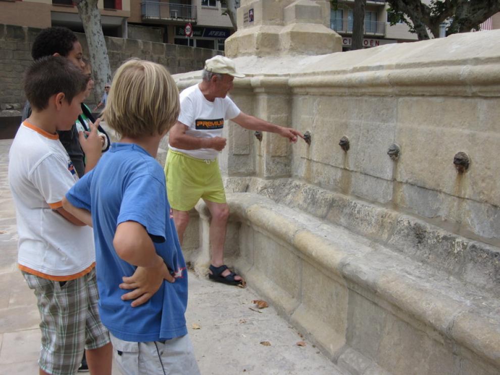 Un anciano explica a las generaciones más jóvenes la leyenda de la fuente en Alcañiz.