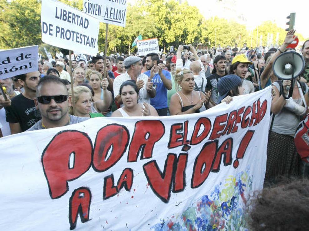Varios indignados muestran su pancarta durante la concentración en la Plaza de Atocha