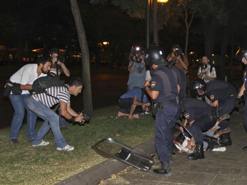 Miembros de la Policía Nacional retienen a un joven durante los disturbios de la noche del jueves