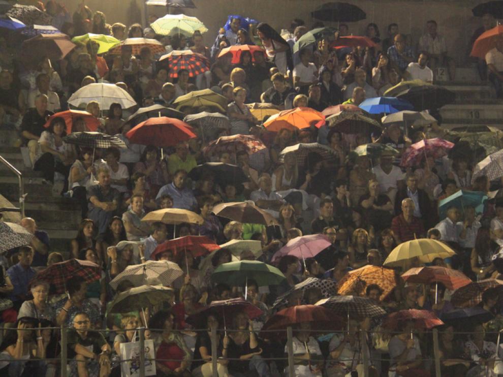 Los asistentes al concierto resguardados bajo los paraguas