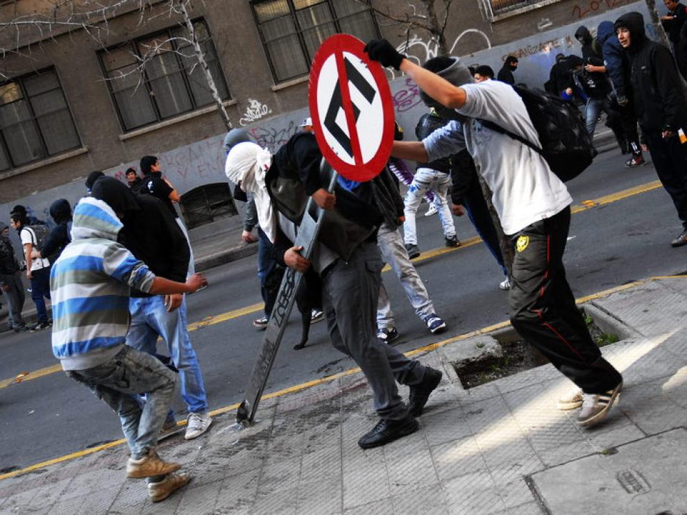 Manifestantes arrancan del suelo una señal en Santiago de Chile