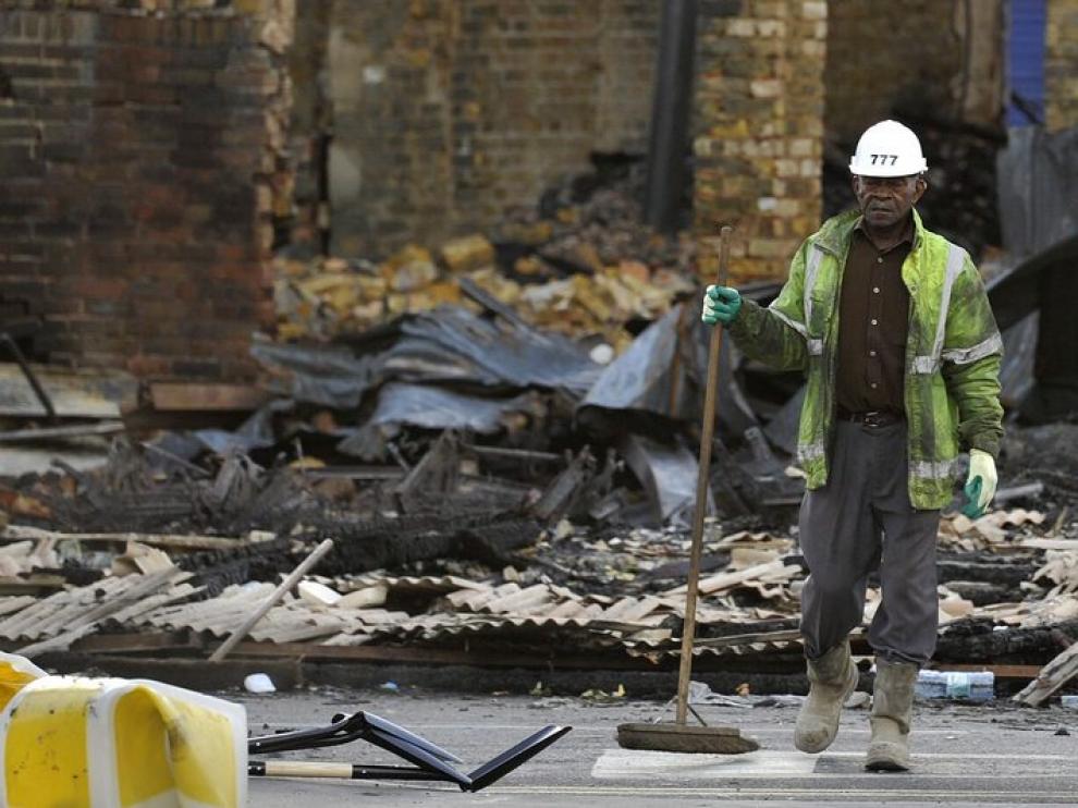 Un trabajador limpia los escombros de lo que era una tienda de muebles al sur de Londres