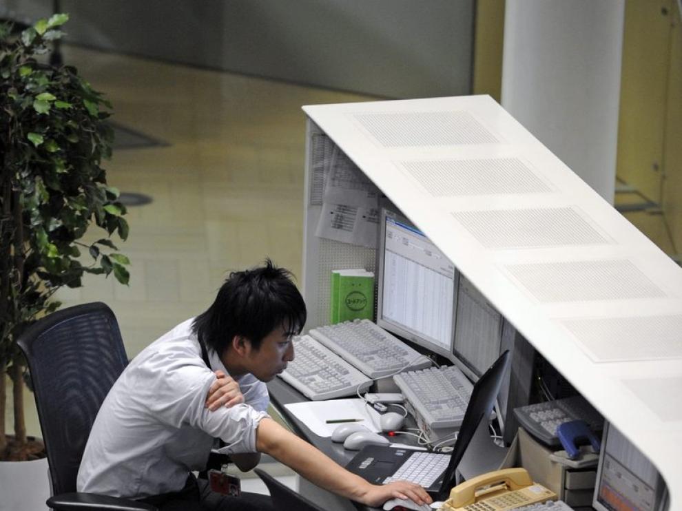 Un corredor de bolsa observa los datos bursátiles en un ordenador en la bolsa de Tokio