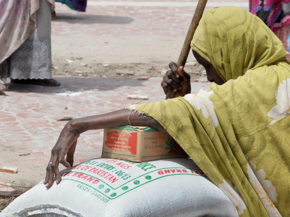 Una anciana refugiada apollada encima de un saco de arroz