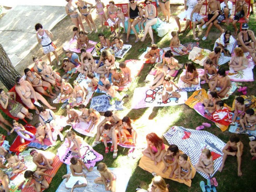 Los bañistas extienden sus toallas para escuchar los cuentos en la piscina de Fraga.