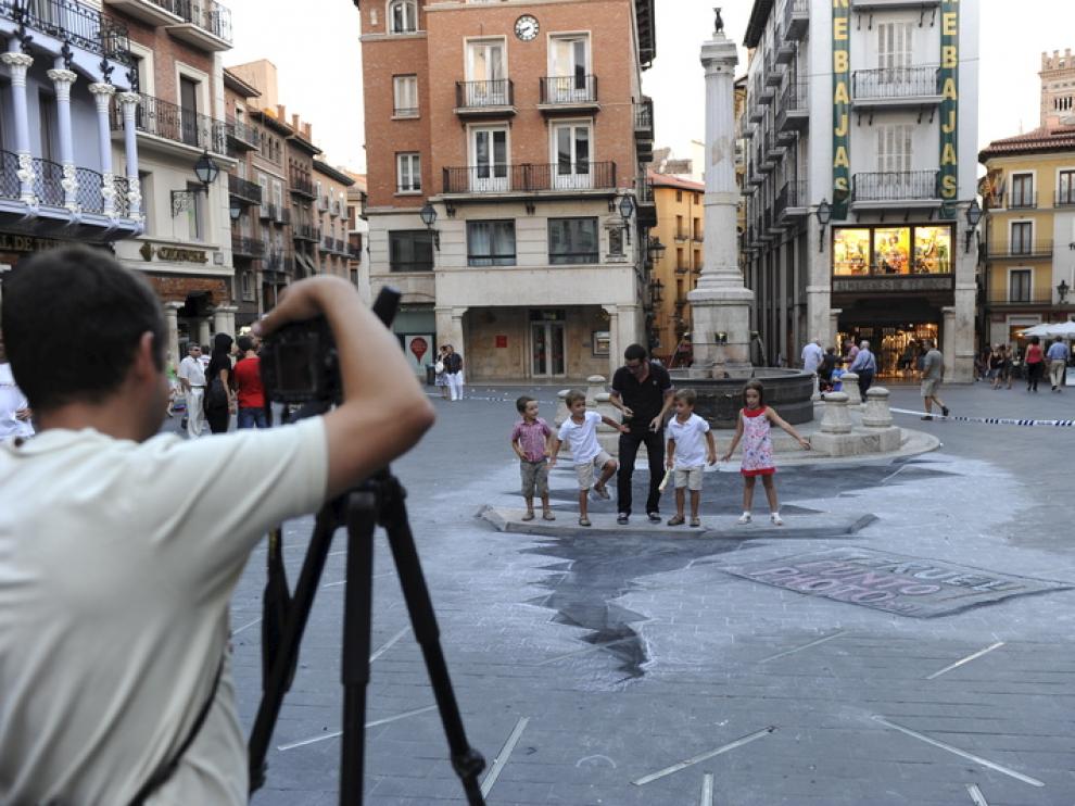 Un grupo de personas juega sobre la pasarela que salva la grieta simulada en la plaza del Torico.
