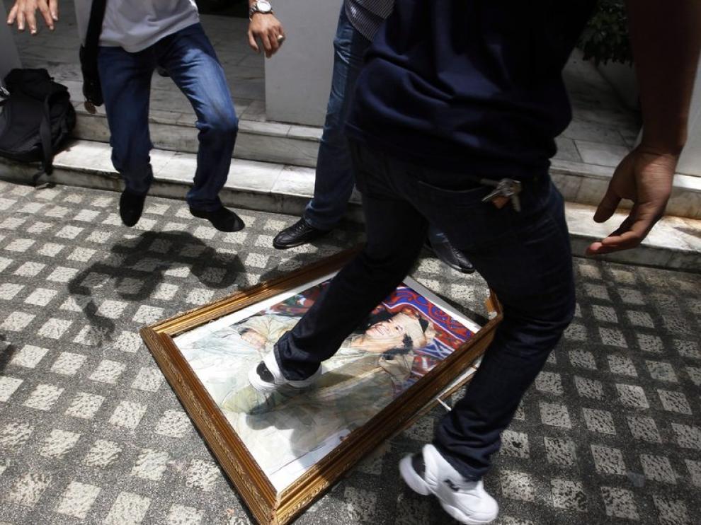 Un libio destroza un retrato del líder libio, Muamar al Gadafi, en el interior de la embajada libia en Manila