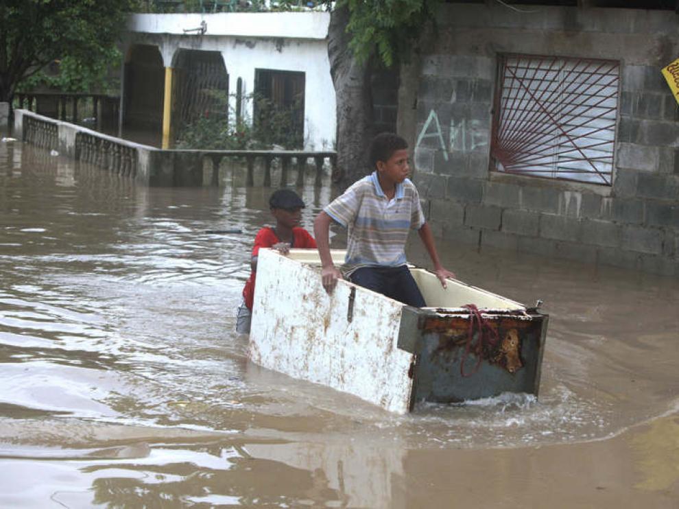 Un joven transportando a otro en medio de una calle inundada