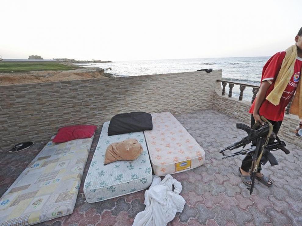 Un rebelde libio, fusil en mano, inspecciona la casa de Saif al-Islam, hijo del líder libio, Muamar al-Gadafi, en Trípoli