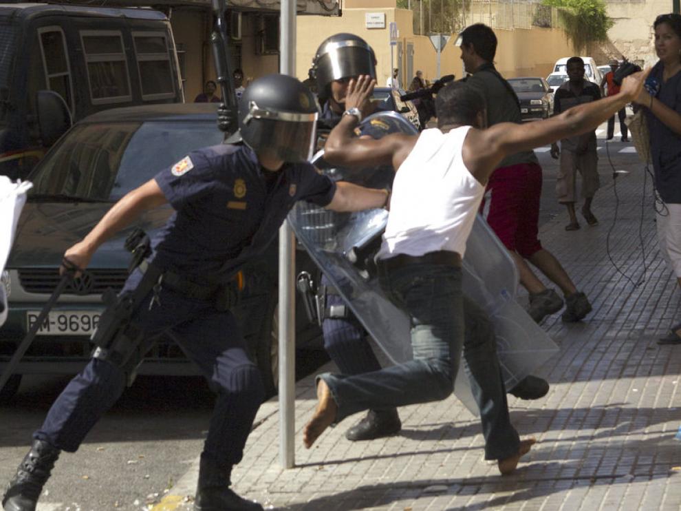Los antidisturbios intentan detener a un ciudadano nigeriano.