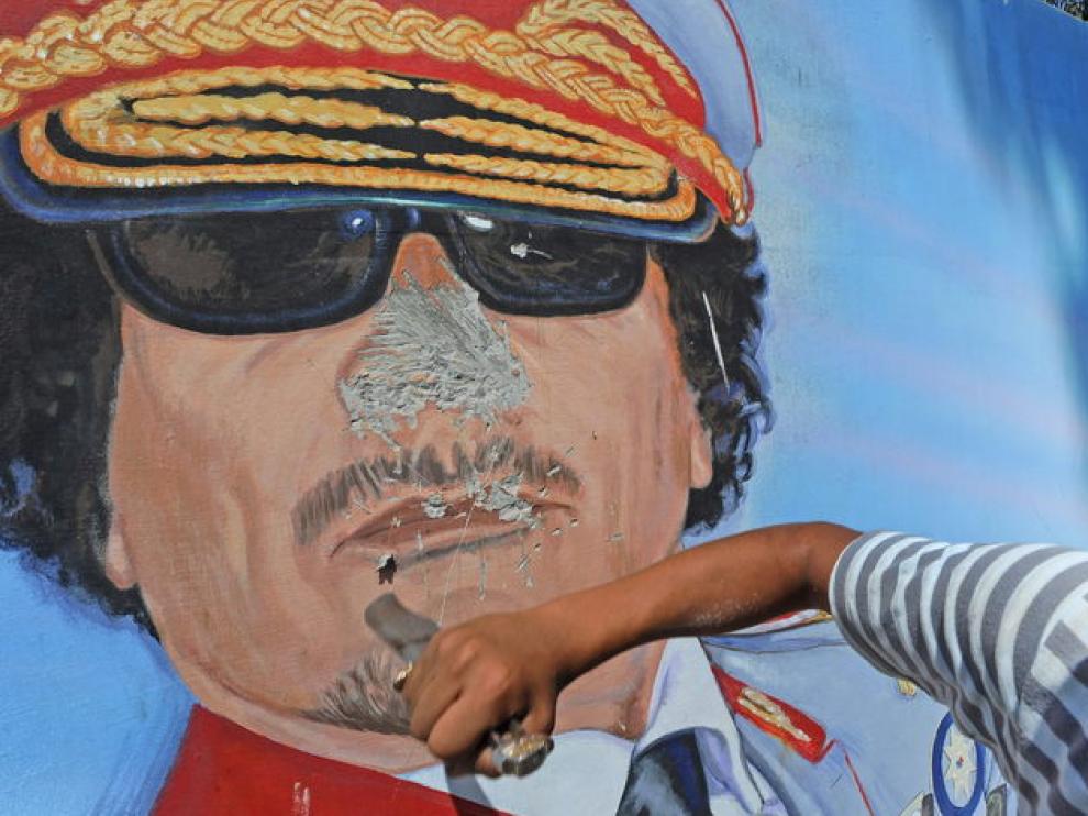 Un hombre destroza un mural de Gadafi