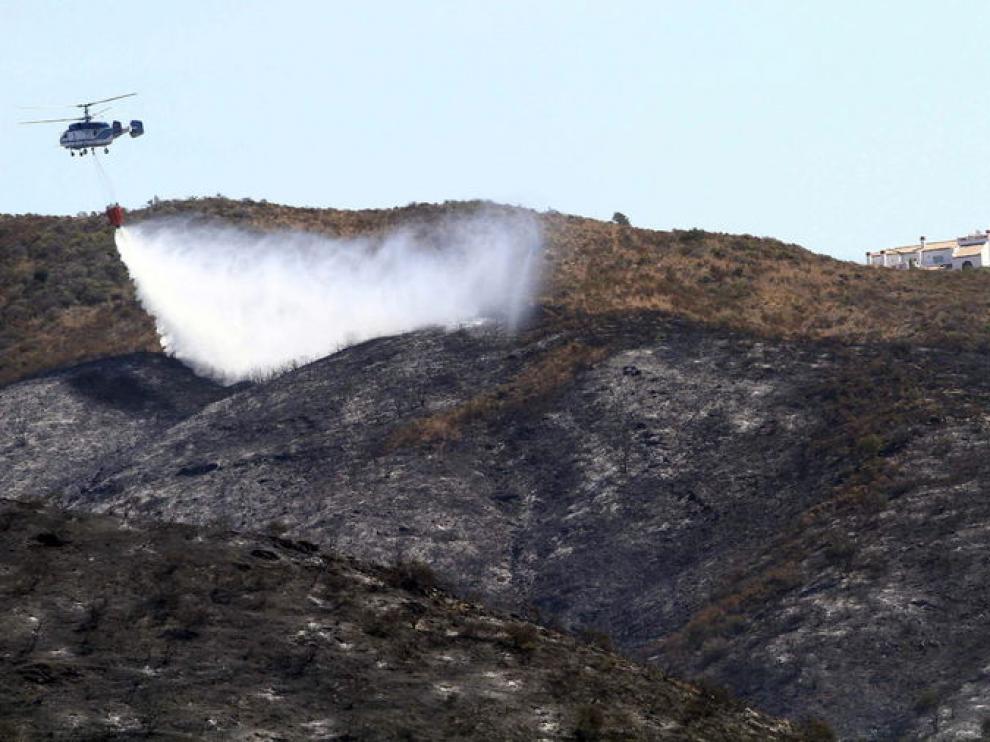 Un helicoptero trabaja en las labores de extinción del incendio de Mijas