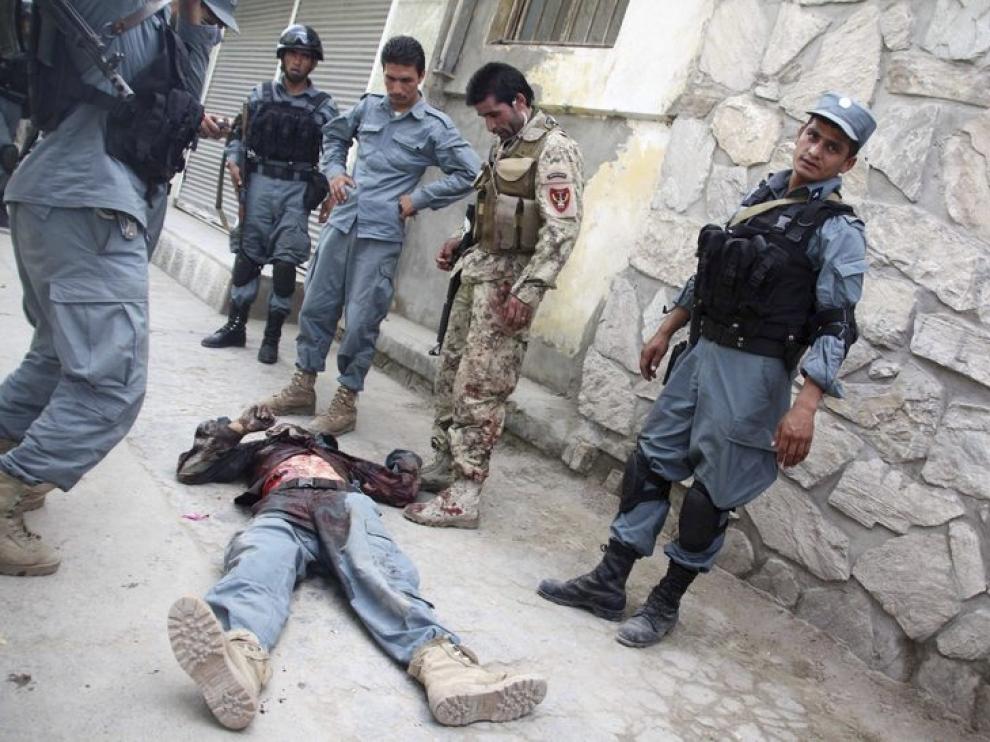 Policías afganos permanecen junto al cuerpo de un compañero muerto en el tiroteo de Kabul
