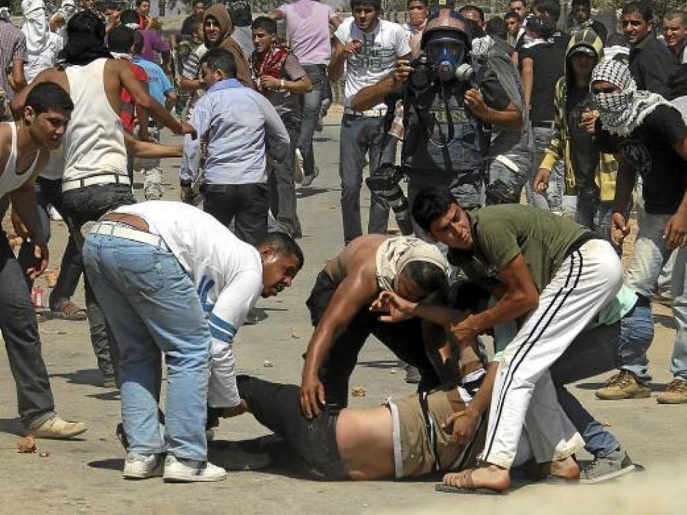 Palestinos ayudan a un hombre herido en un enfrentamiento con tropas israelíes, ayer en Qusra.
