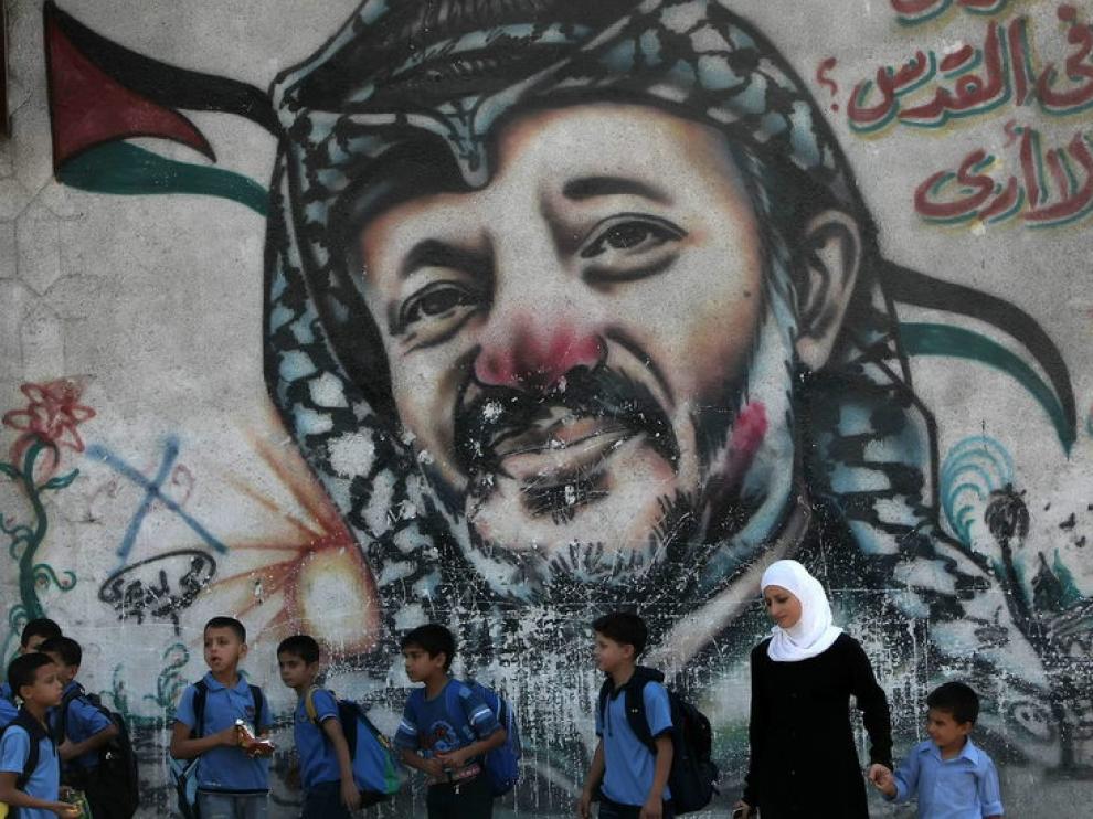 Escolares ante un mural con la foto de Arafat, en Gaza