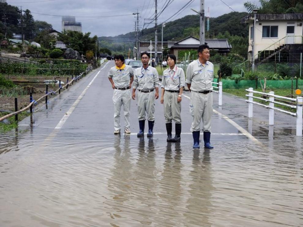 Cuatro inspectores observan una calle inundada en Iwakura
