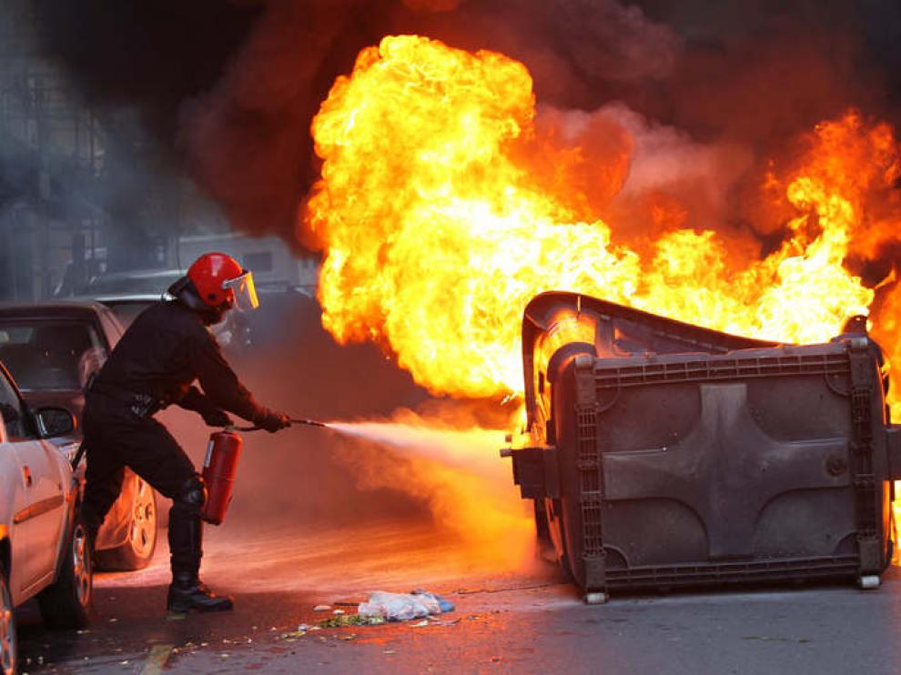 Un ertzaina sofoca el fuego en un contenedor