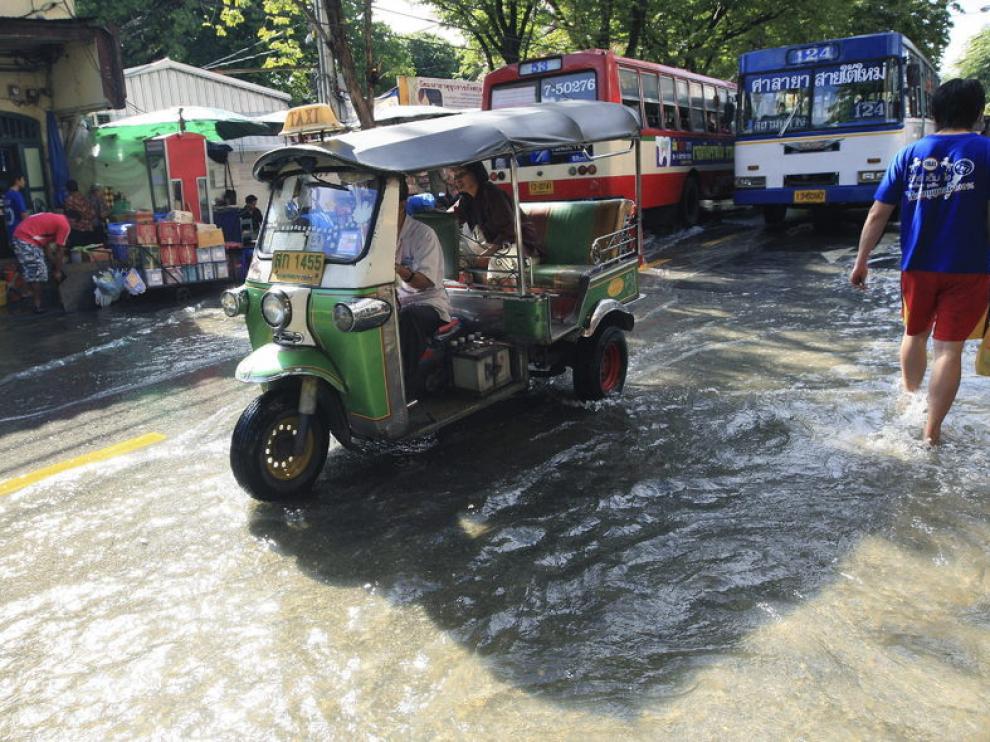 Un tuk tuk circula por las calles inundadas de Bangkok