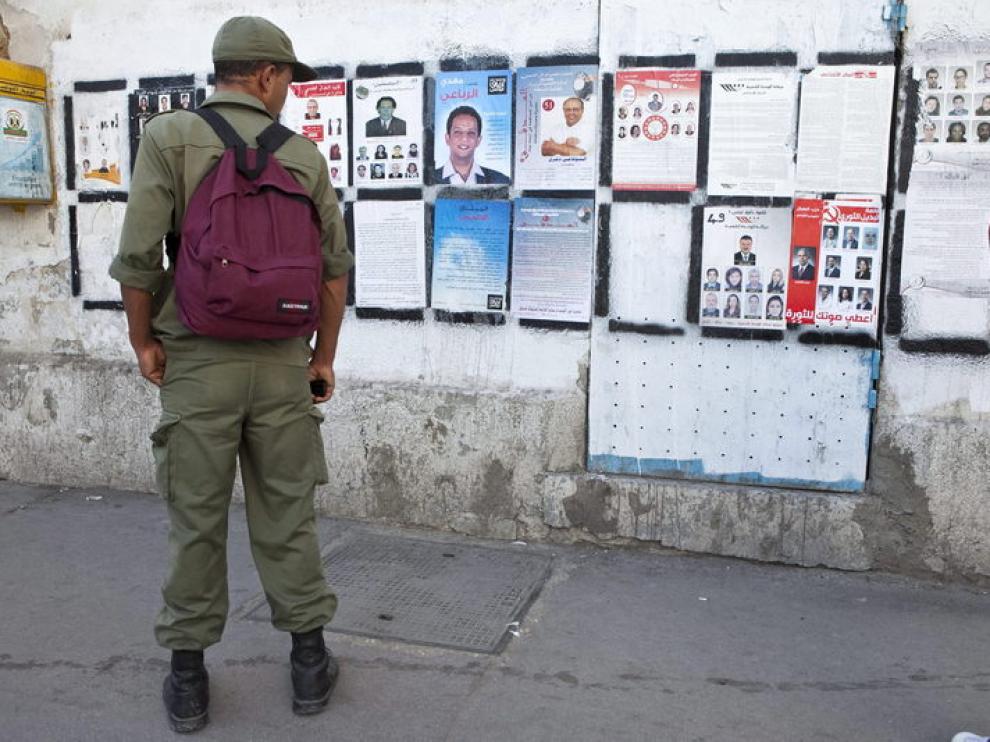 Un soldado tunecino observa varios carteles electorales