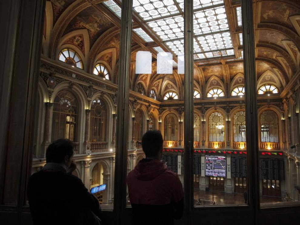 Dos personas observan los paneles de la Bolsa de Madrid