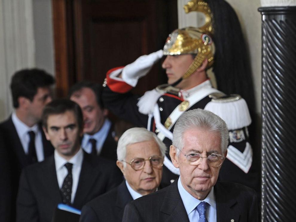 El excomisario europeo y senador italiano, Mario Monti (dcha), sale de la rueda de prensa ofrecida para presentar la lista de ministros tras aceptar el cargo de presidente del Gobierno de Italia