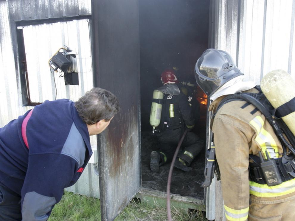 Unos bomberos observan desde el exterior de las instalaciones la actuación de sus compañeros.