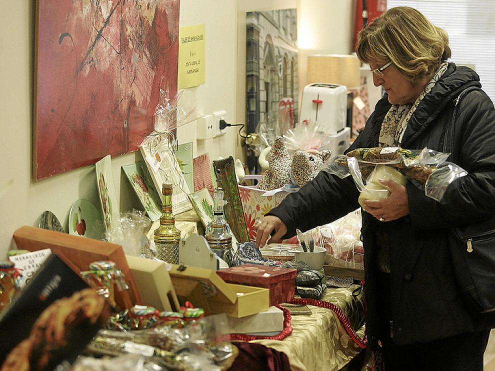 Una mujer selecciona algunos productos de alimentación del mercadillo de la AECC.