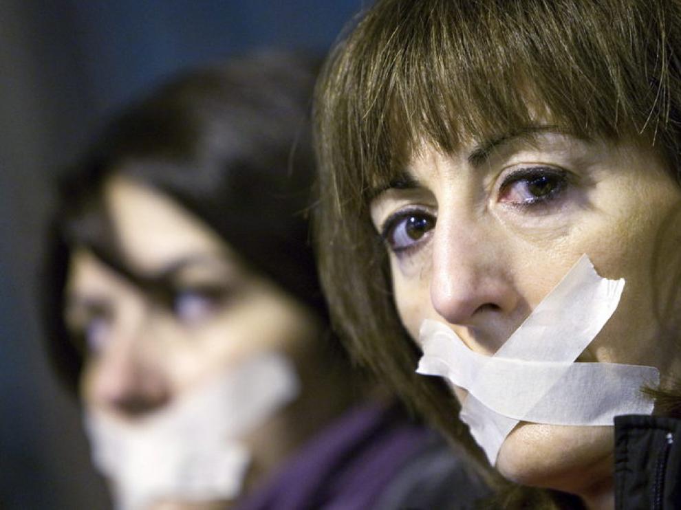 Dos mujeres se tapan la boca durante una manifestación contra la violencia de género en Zaragoza