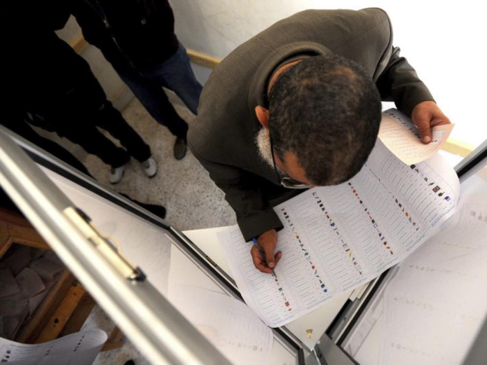 Un hombre cumplimenta su papeleta antes de ejercer su derecho al voto en El Cairo