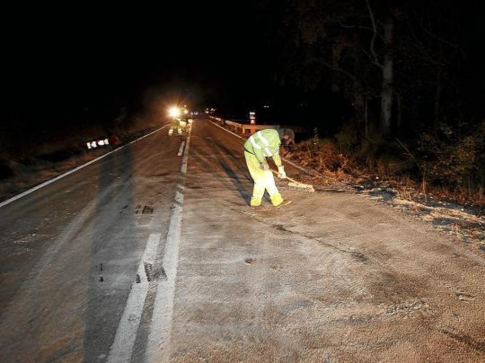 Operarios de Fomento retiran la arena vertida sobre la N-330 por el camión accidentado.