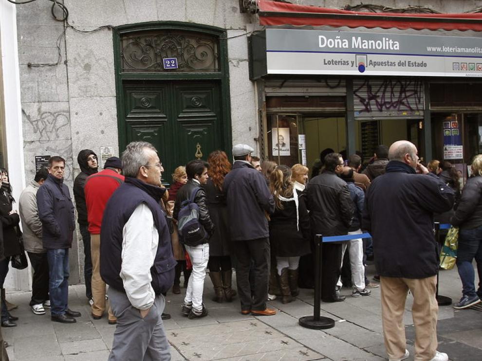 Decenas de personas esperan su turno ante una administración de lotería en Madrid