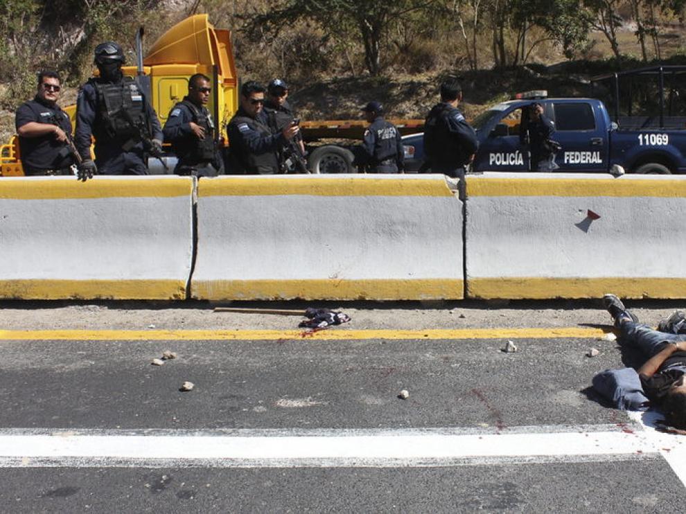 Agentes federales observan el cuerpo de uno de los dos muertos que resultaron de un enfrentamiento entre estudiantes y policías