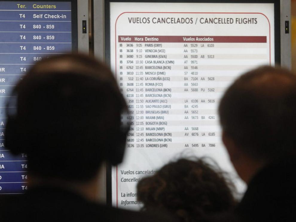 Pasajeros afectados por la huelga de pilotos de Iberia observan en la T-4